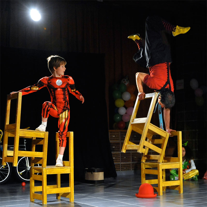 Un acrobate épatant un jeune enfant partageant la scène avec lui et supportant les agitations du public de Dijon, conquise par leurs prestation fabuleuses , dans un studio réformé en novembre. Animmagic compagnie d'animation pour noël  Rhône alpes.