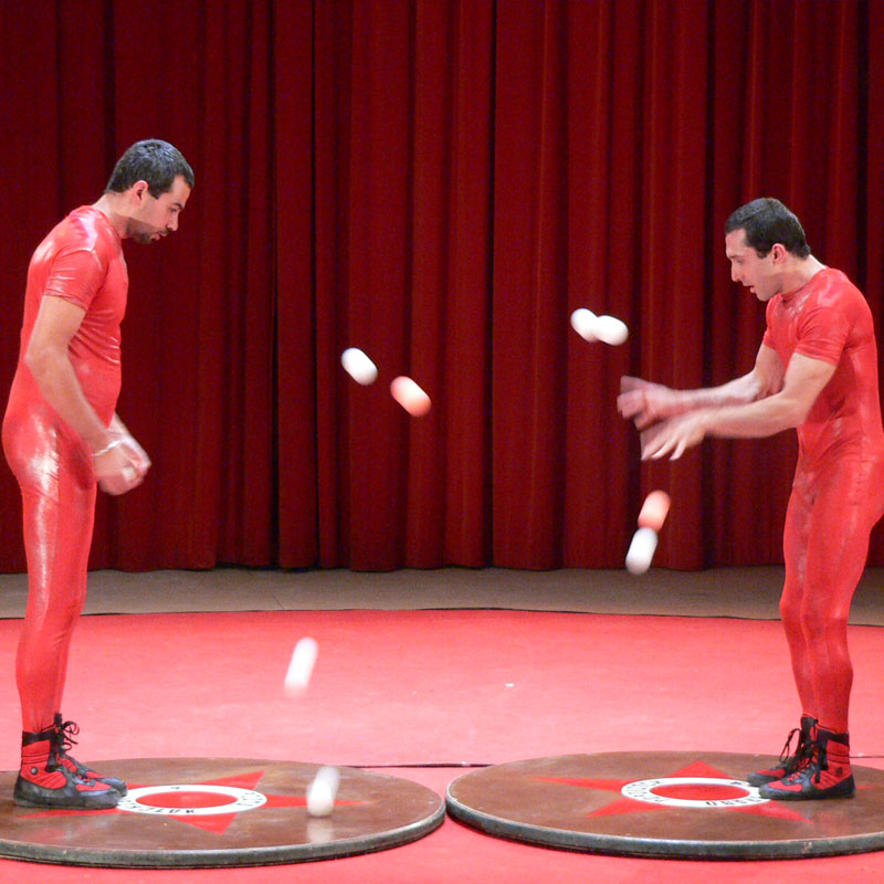 Deux jongleurs supervisent leurs balles, sur la scène, prêt à faire leurs show depuis le hall de Vénissieux. Animmagic spectacle de clown Lyon.