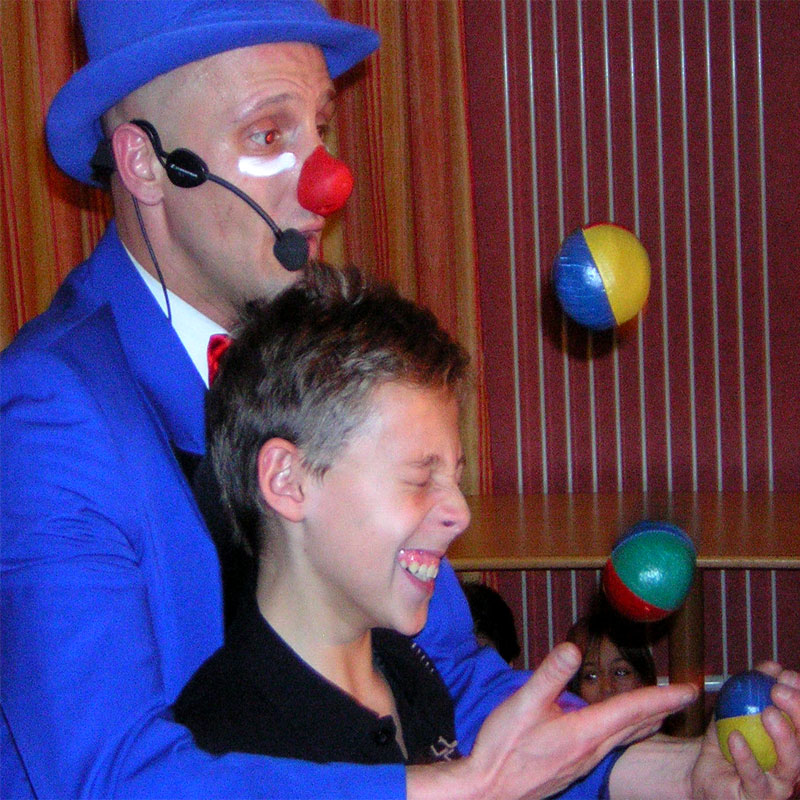 Un clown improvisé donnant de la joie à un enfant sur la piste flamboyante de Villeurbanne, rappelant  un carnaval en ville après un déjeuner avec des acheteurs d'une même communauté artistique. Animmagic animation magie de noël pour tout âges Rhône Alpes.
